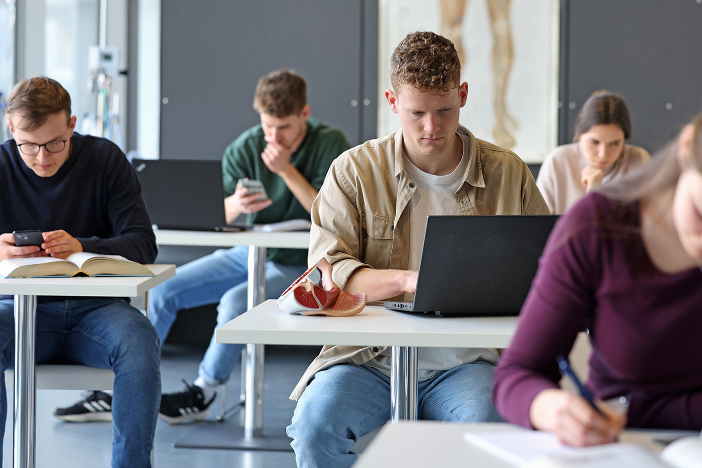 Mehrere Pflegeschüler sitzen im Klassenraum einer Pflegeschule und lernen.