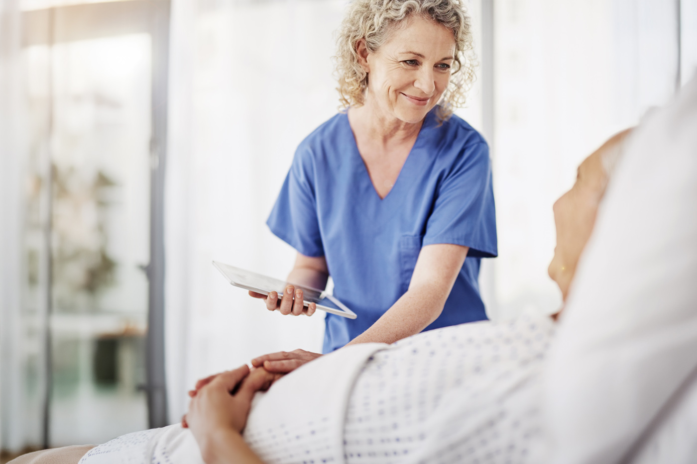 Eine Pflegekraft betreut einen Patienten am Bett.