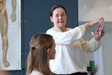 Eine Verantwortliche für IBF steht in einem Schulungsraum und hält ein künstliches Herz in der Hand.