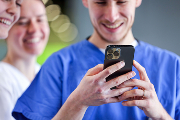 Ein Azubi aus der Pflege tippt auf seinem Smartphone