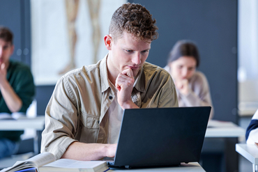 Ein Seminarteilnehmer sitzt in einem Schulungsraum und lernt mit einem Laptop.