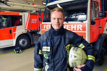 Ein Feuerwehrmann steht vor einem Einsatzwagen